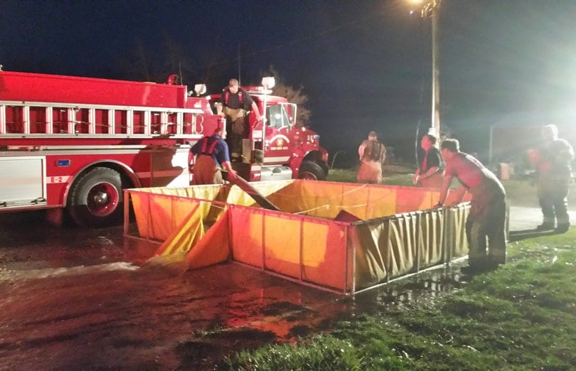 Firefighters filling a Husky portable folding frame drop tank